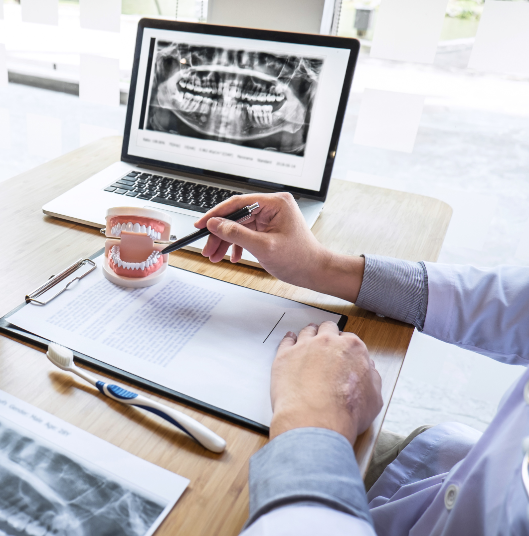 A dentist is looking at an x-ray of a patient 's teeth on a laptop computer.
