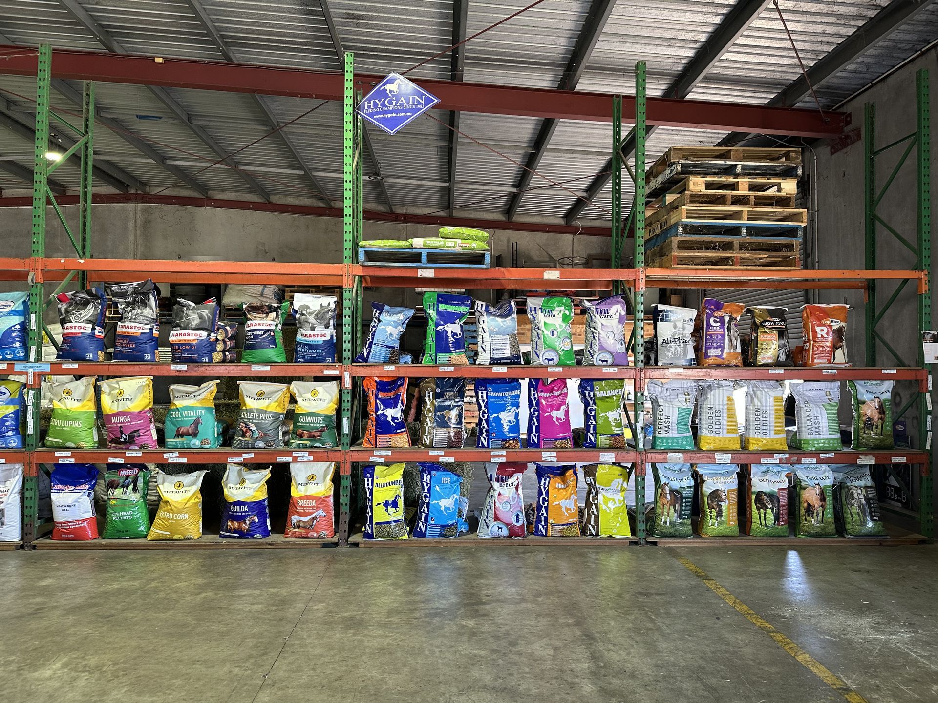 Shelves stocked with various dog food bags inside a warehouse setting. — North Coast Stock Feeds in Wardell, NSW