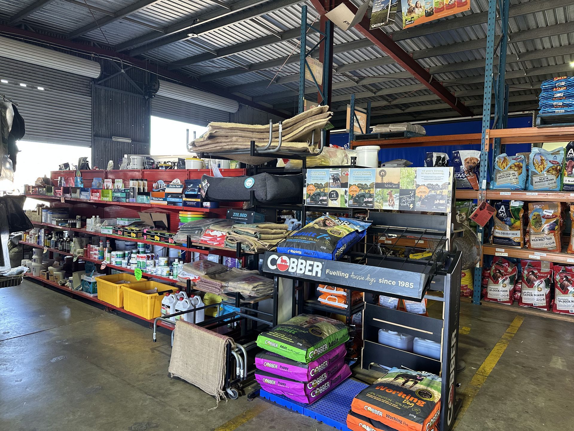 Shelves stocked with pet supplies in a warehouse, including food and toys, with various brands displayed. — North Coast Stock Feeds in Wardell, NSW