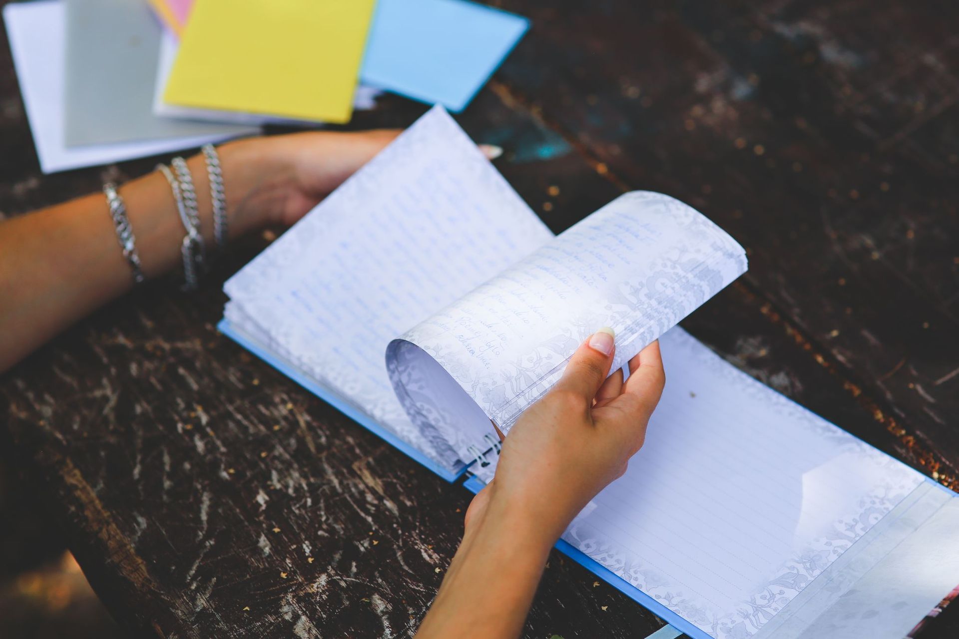 Hands reviewing handwritten notes and colorful planning tabs in an open notebook.