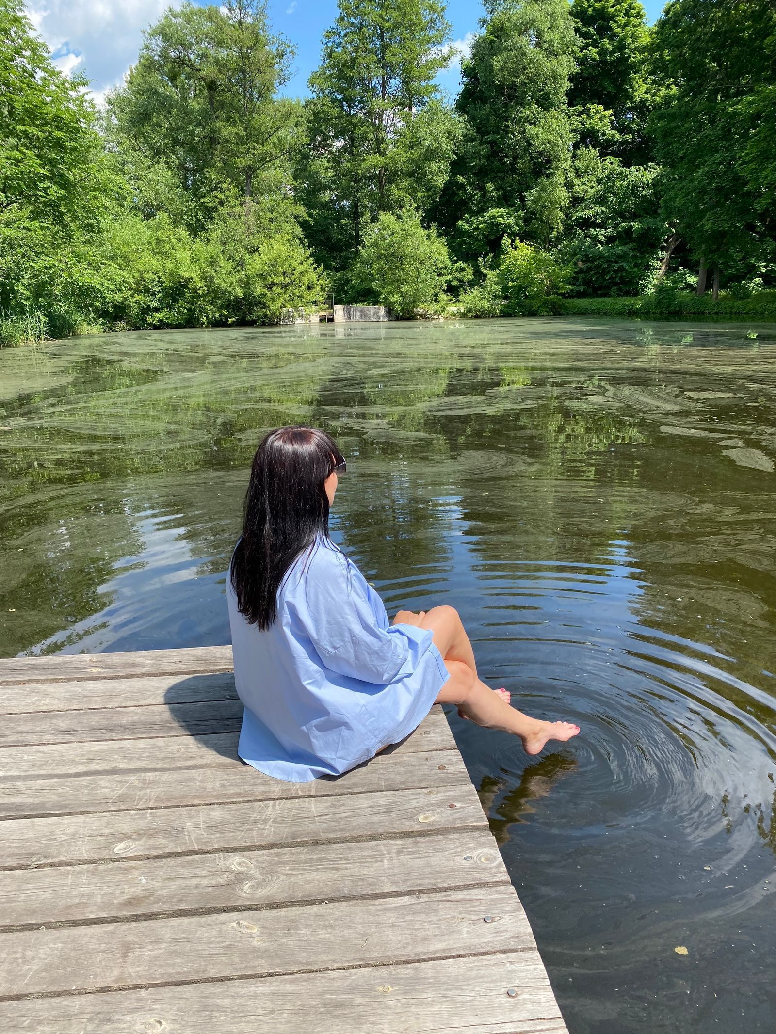 Woman sitting beside a lake watching ripples in the water.