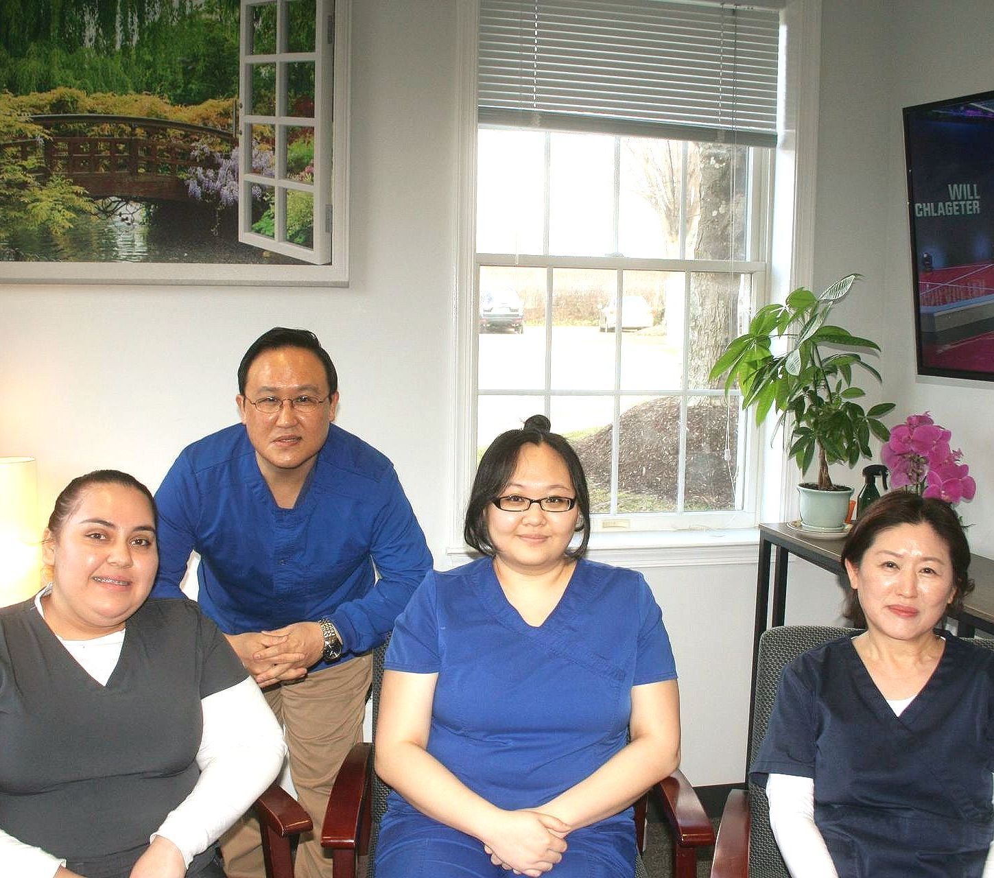 Dr. Cho's Team are posing for a picture in front of a window .