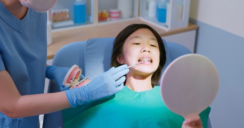 Dentist examining a patient's teeth with a mirror in a dental office.