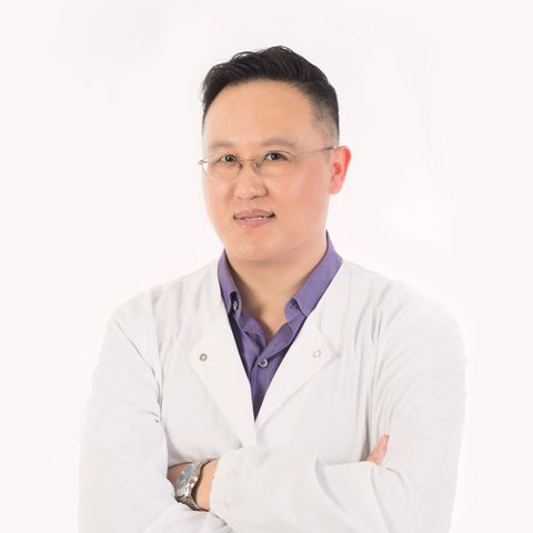 Dr. Cho in a white coat and purple shirt is standing with his arms crossed .