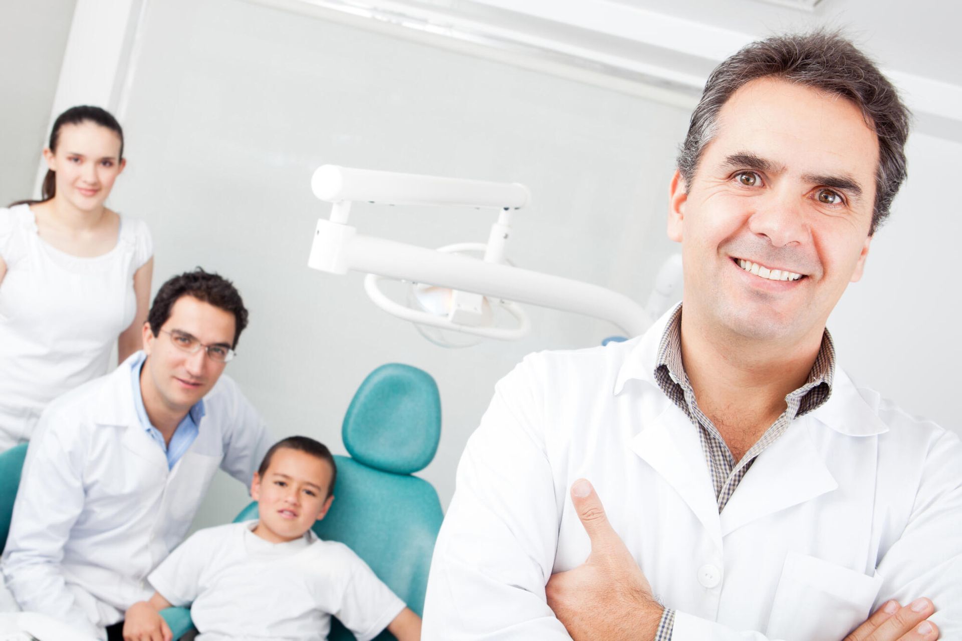 A dentist is standing in front of a family in a dental office.