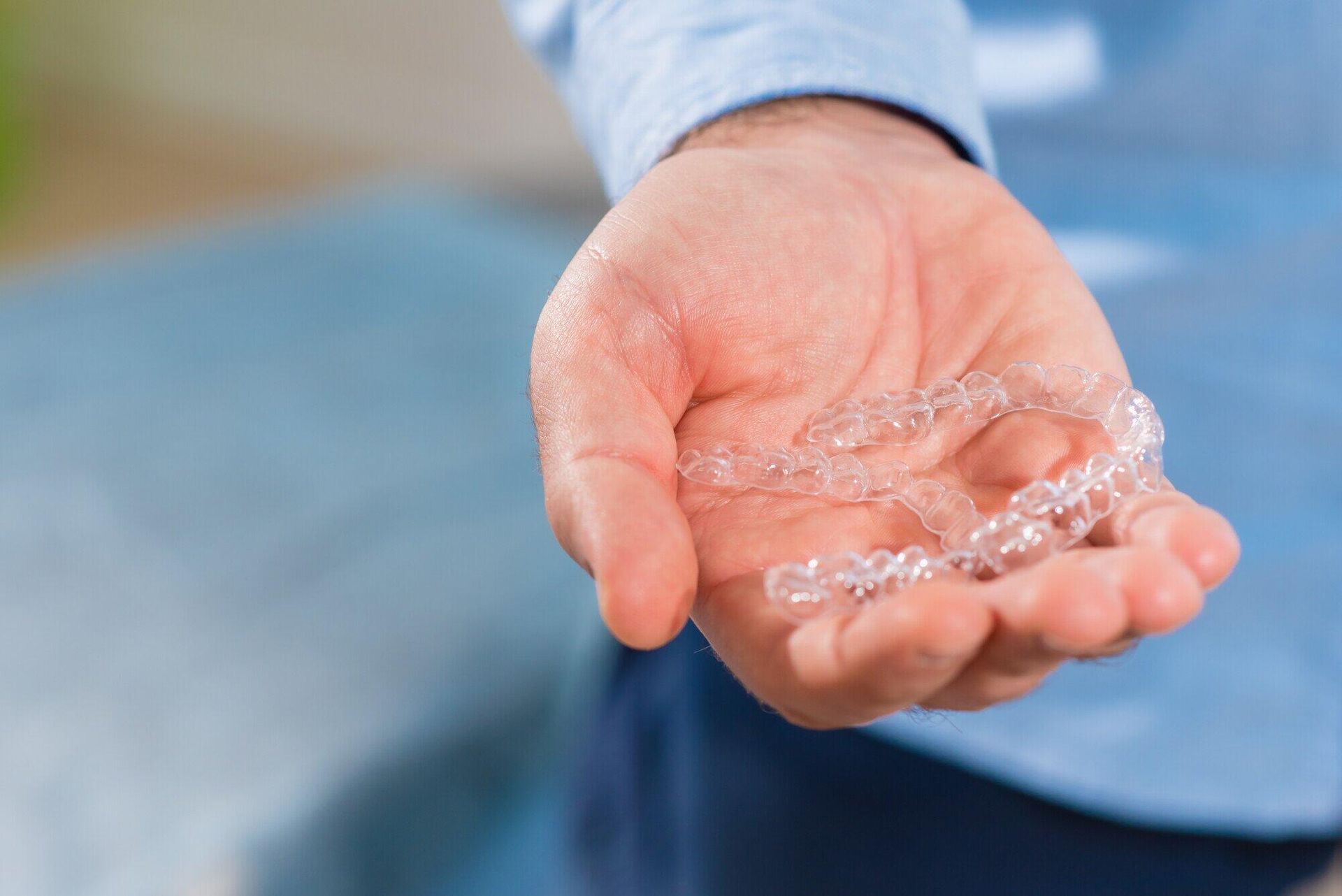 A person is holding a pair of clear braces in their hand.