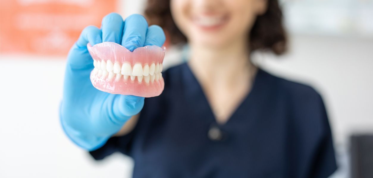 A dentist is holding a denture in her hand.
