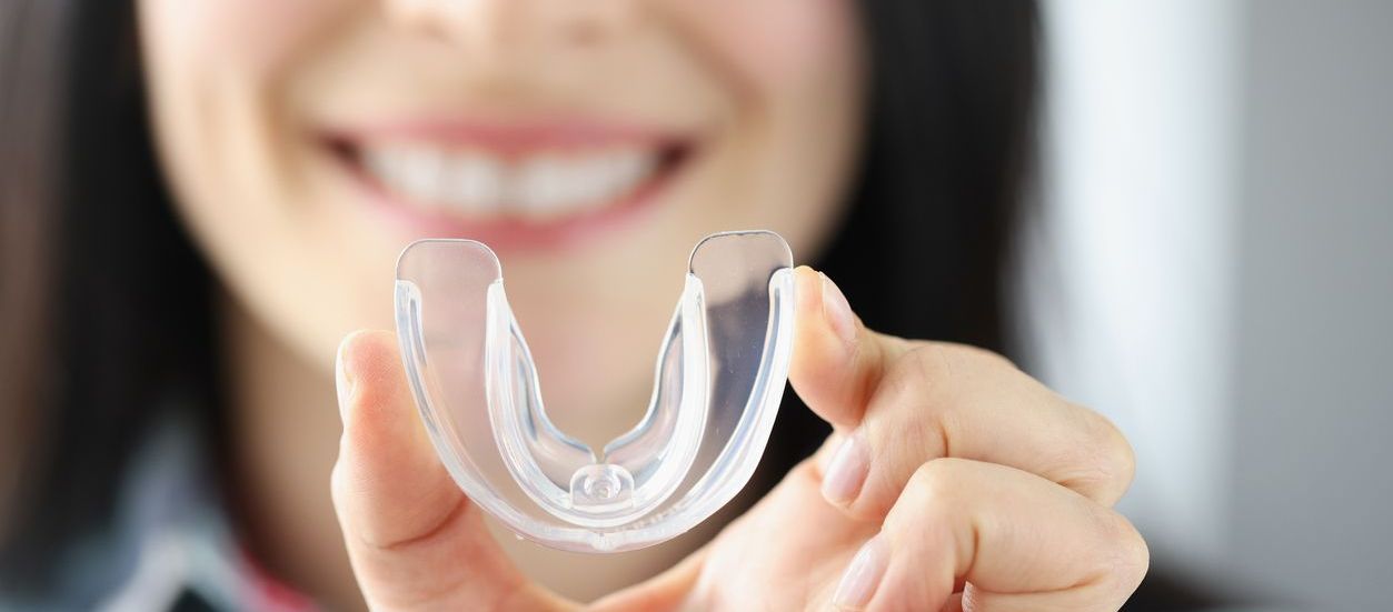 A woman is holding a clear mouth guard in her hand.