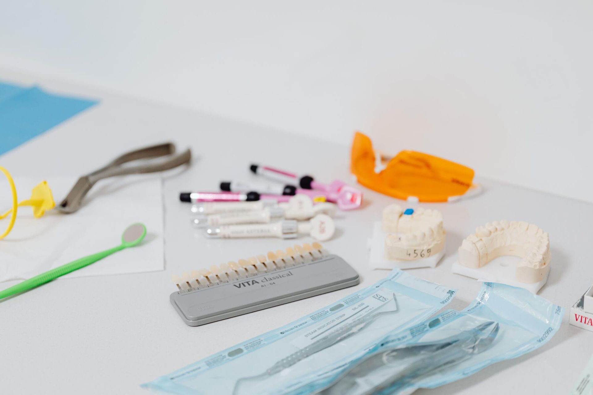 Assorted medical and craft supplies arranged on a white table, including gloves, masks, scissors, and tools