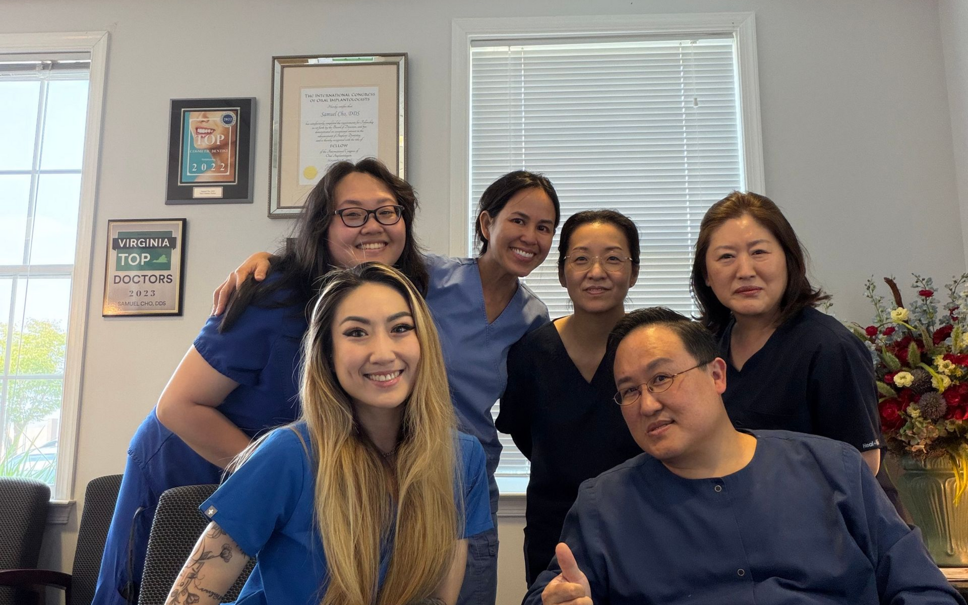 Dr. Cho's Team are posing for a picture in front of a window .