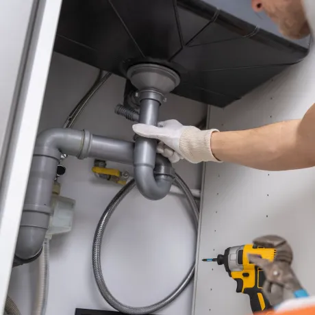 Maese Solutions Electric Plumbing HVAC - A man is fixing a sink with a drill.