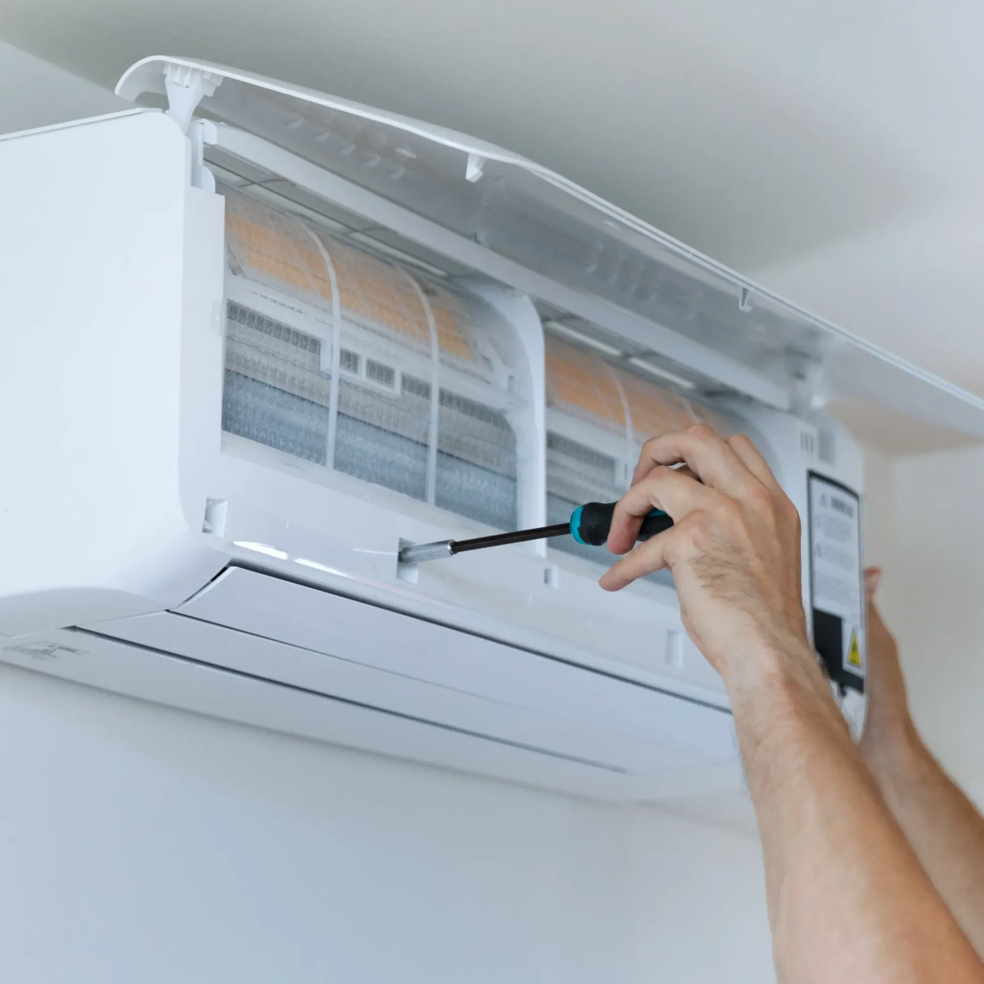 Maese Solutions Electric Plumbing HVAC - A person is fixing an air conditioner with a screwdriver.