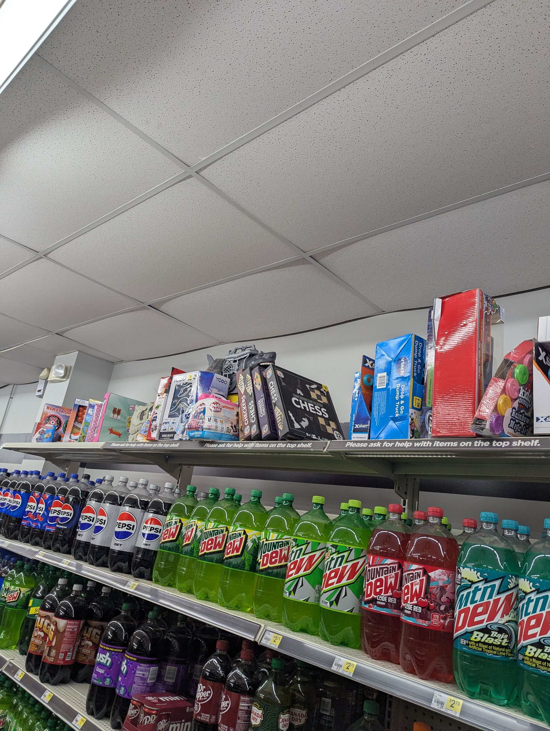 Shelves in a store stocked with rows of various soda bottles, including Pepsi, Mountain Dew, and Fanta.