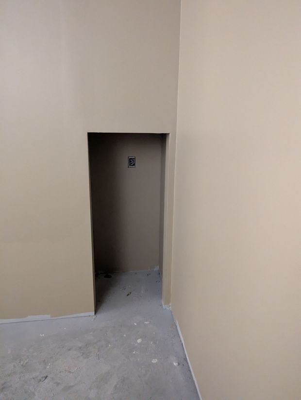 A recessed wall alcove in an unfinished room with beige painted walls and a concrete floor.