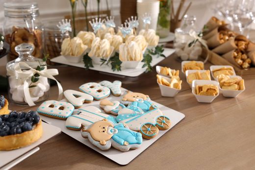 Assorted pastel frosted cookies and pastries arranged on platters at a dessert table