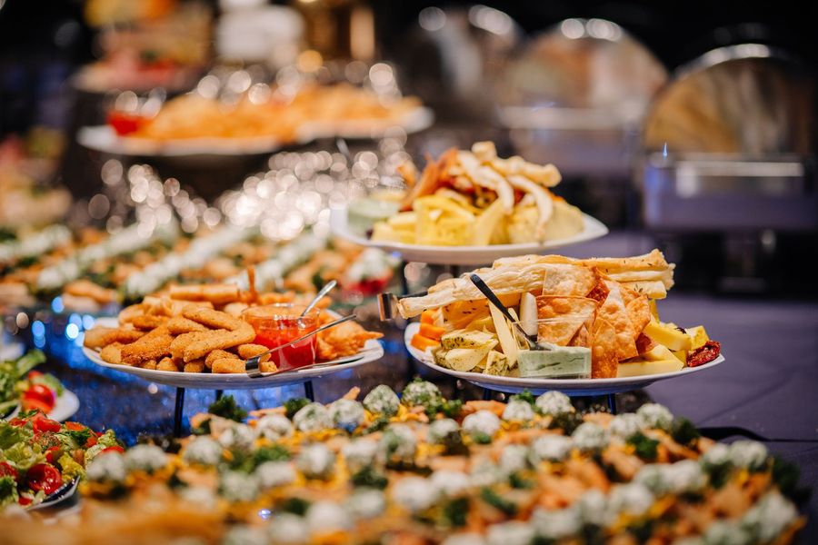 Buffet table with assorted appetizers on tiered trays and platters in a warm, blurred banquet setting