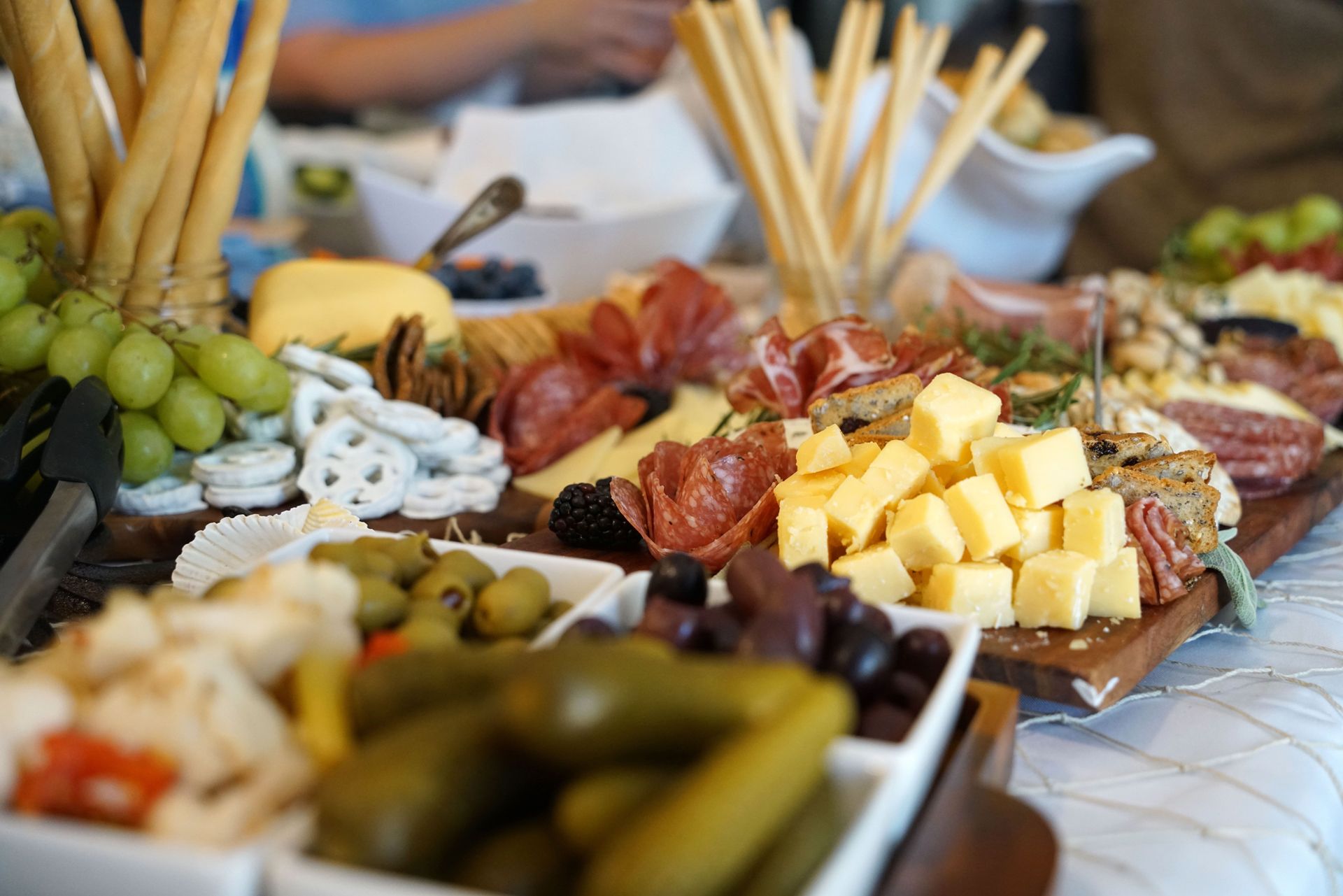 Charcuterie and cheese board with grapes, olives, pickles, breads, and skewers on a table