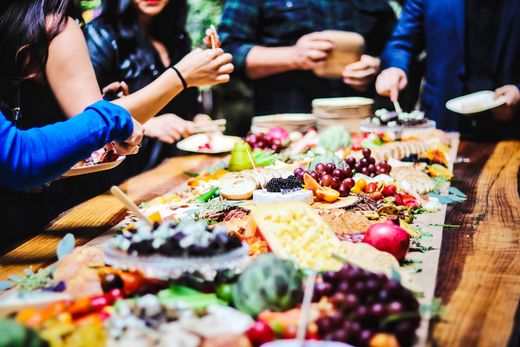 People sharing plates of colorful food at a long table during a meal