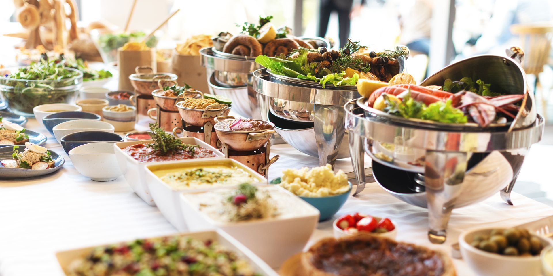 A buffet table with salads, soups, and plated dishes in a bright dining setting.