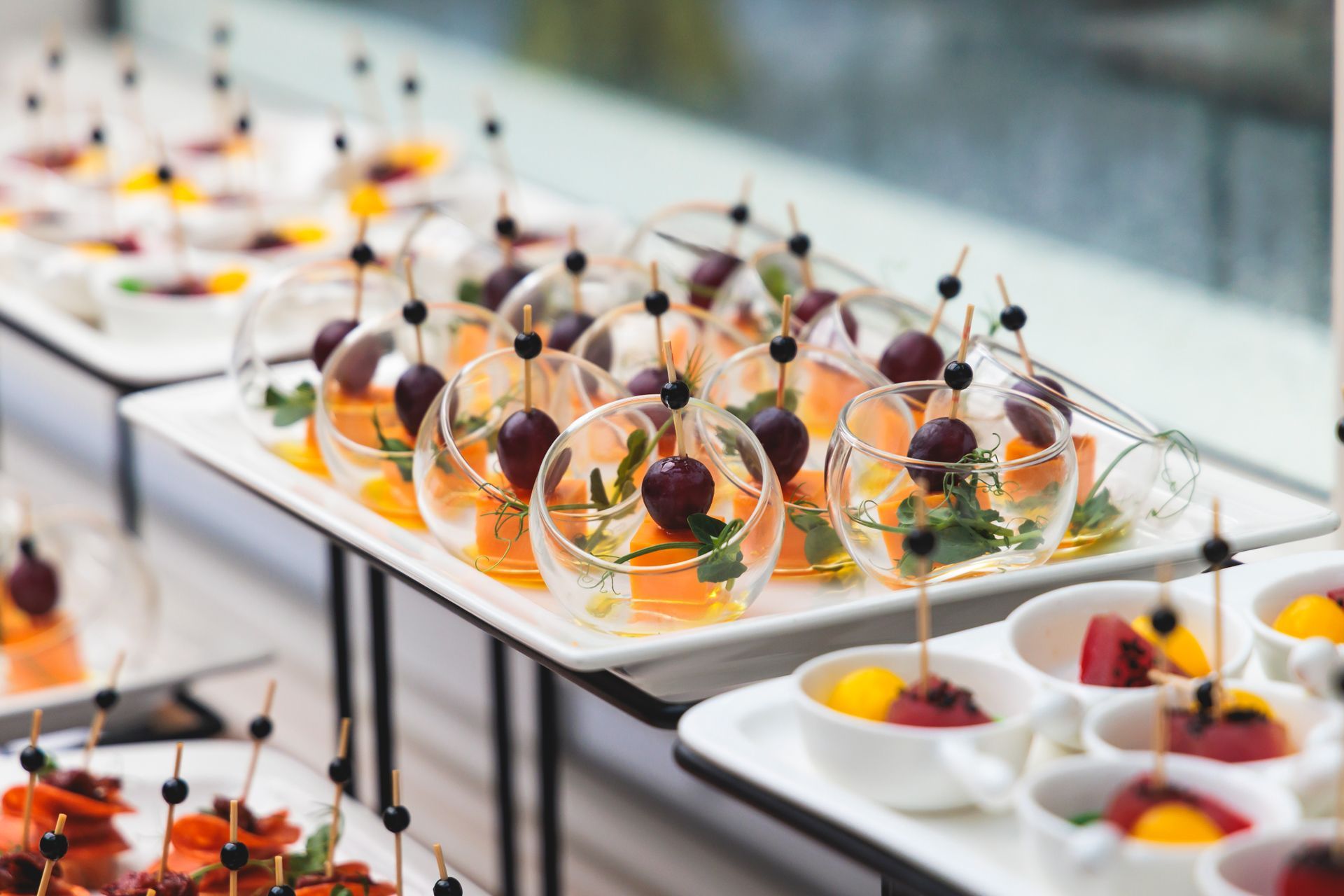 Plated gourmet desserts in glass bowls on a buffet table with orange garnish and chocolate decorations