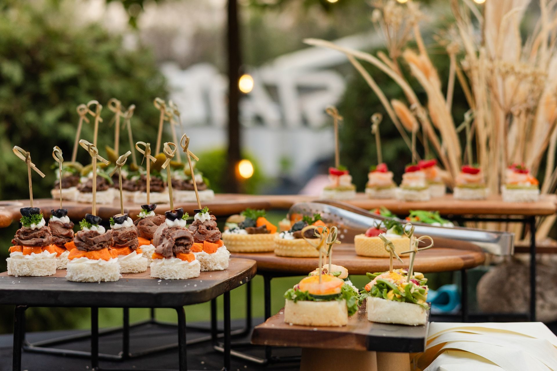 Outdoor buffet table with assorted appetizers and skewered hors d'oeuvres at a garden event