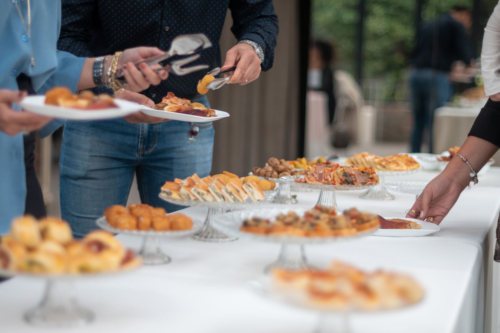 People serving appetizers from platters at a buffet table in a catered event