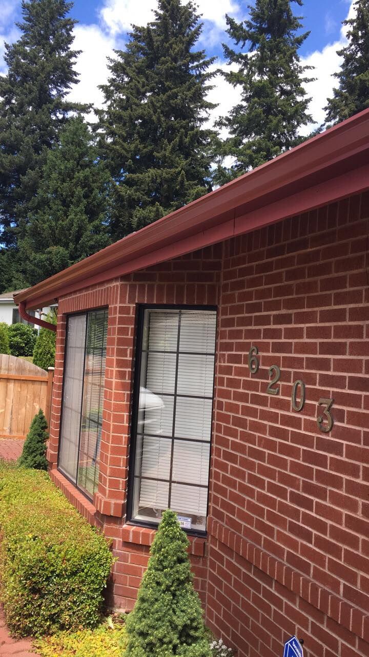 A red brick house with a window and trees in the background