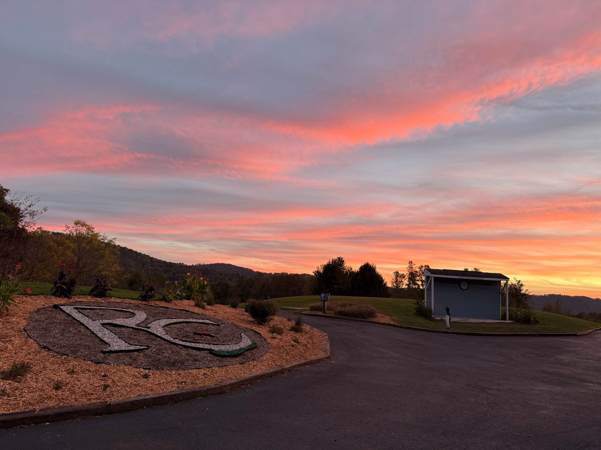Sunrise over rolling hills with a sign reading 