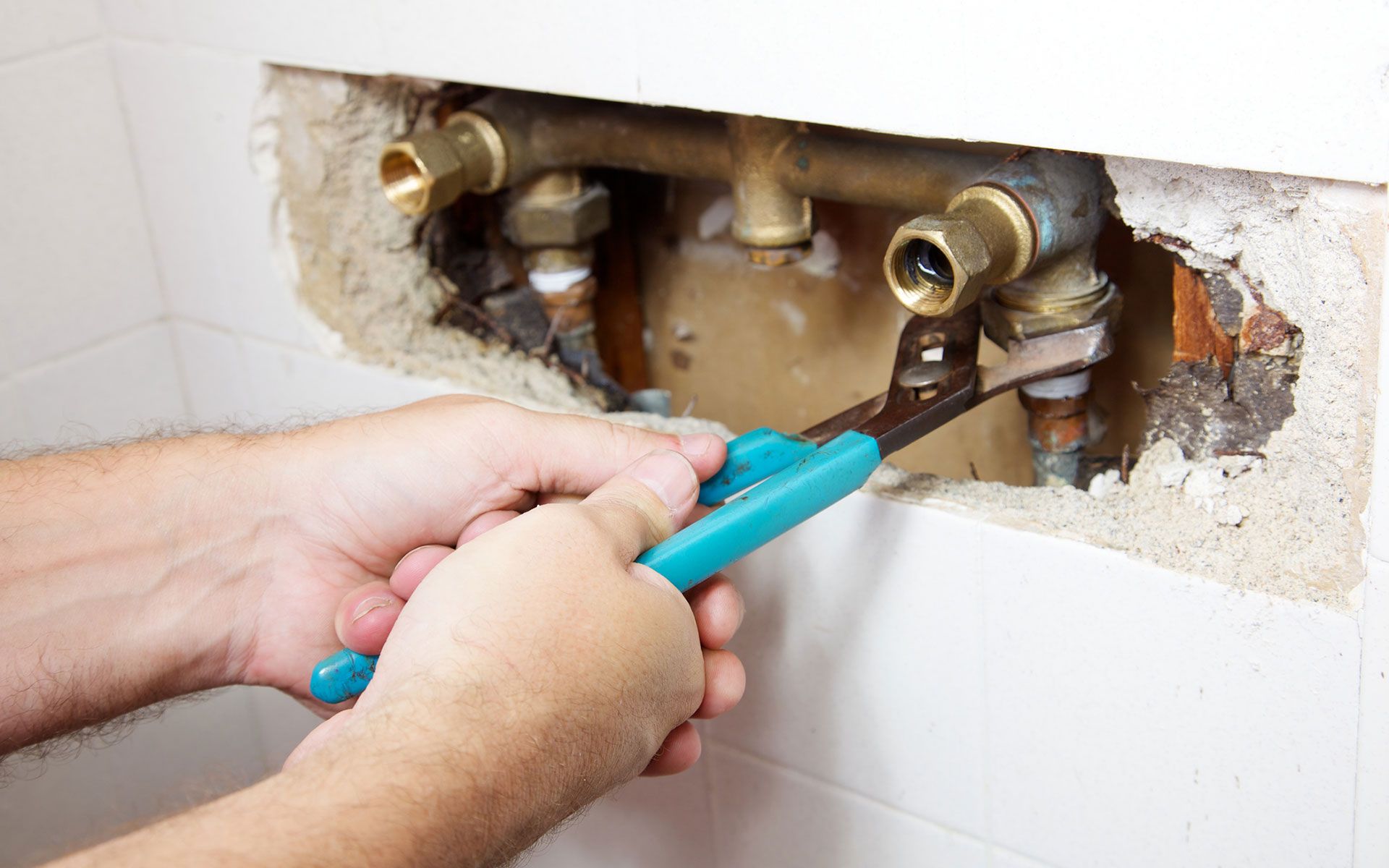 A person is fixing a pipe with a wrench.