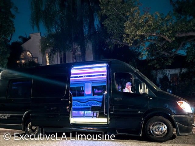 Black limousine with lit interior parked at night on a residential street