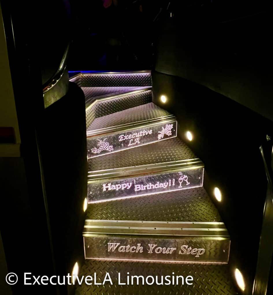 Illuminated limousine stairs with “Happy Birthday” and “Watch Your Step” text in a dark interior