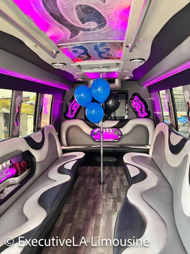 Interior of a luxury limousine with purple lighting and blue balloons in the center.