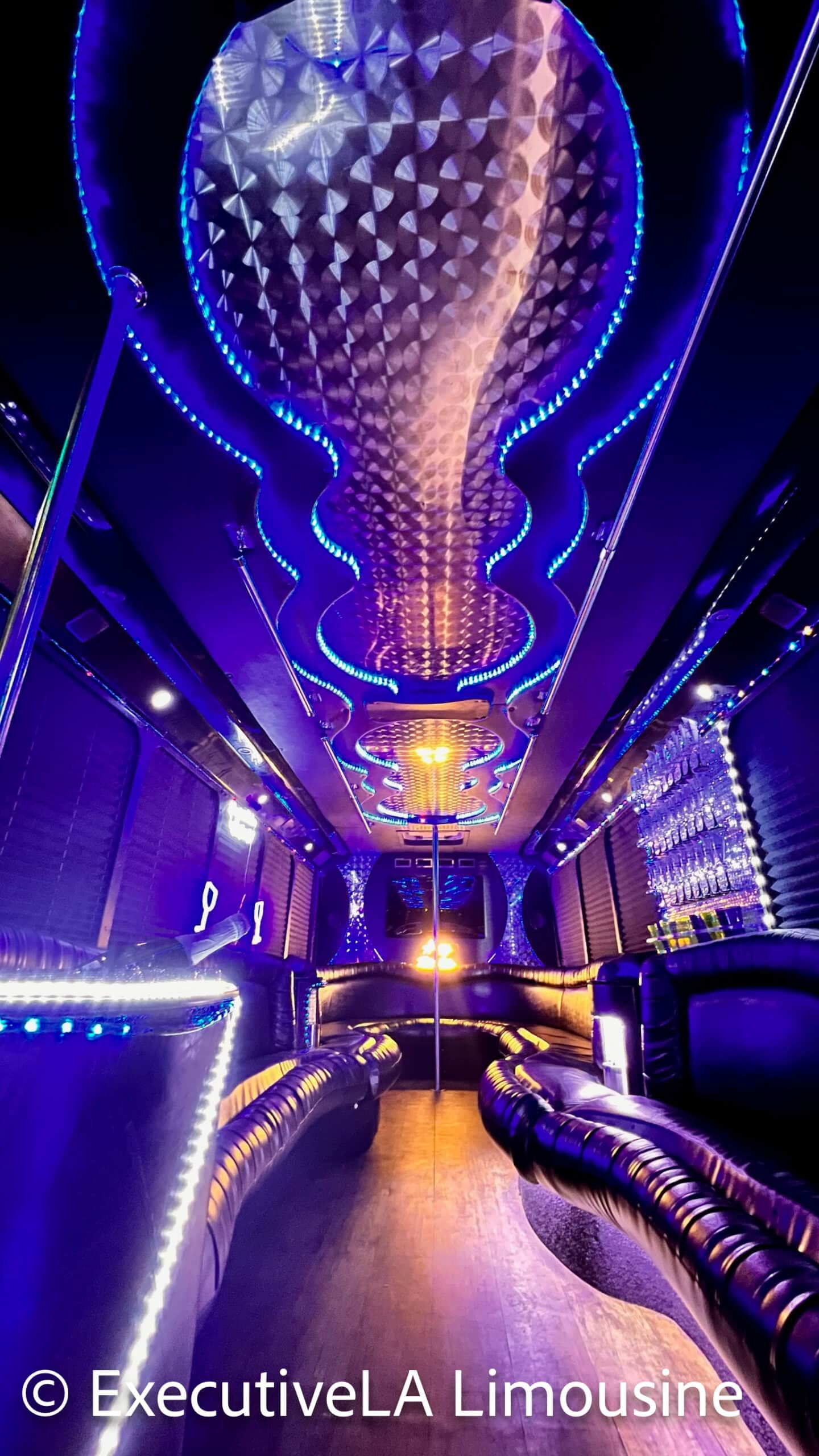 Purple-lit luxury limousine interior with mirrored ceiling, plush seats, and aisle seating