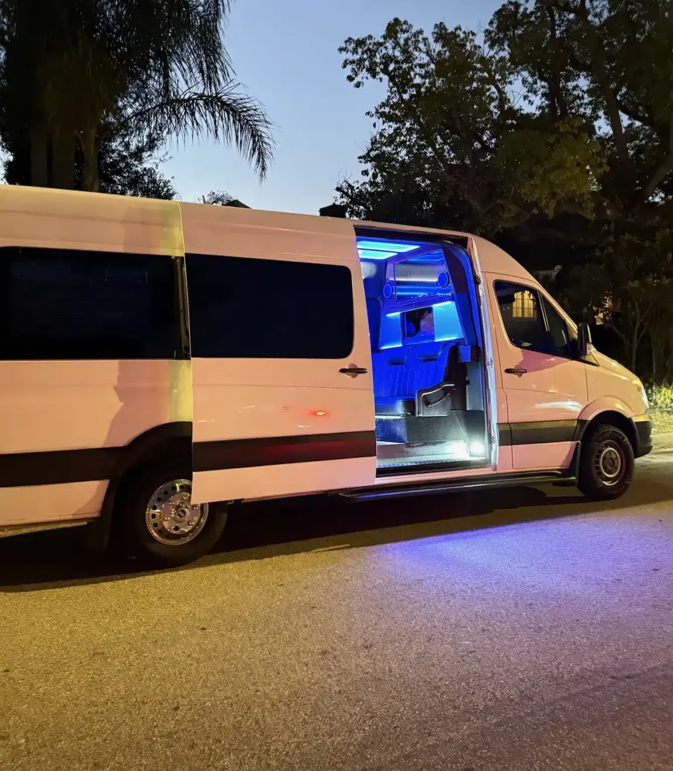 White van parked at night with open sliding door glowing blue inside