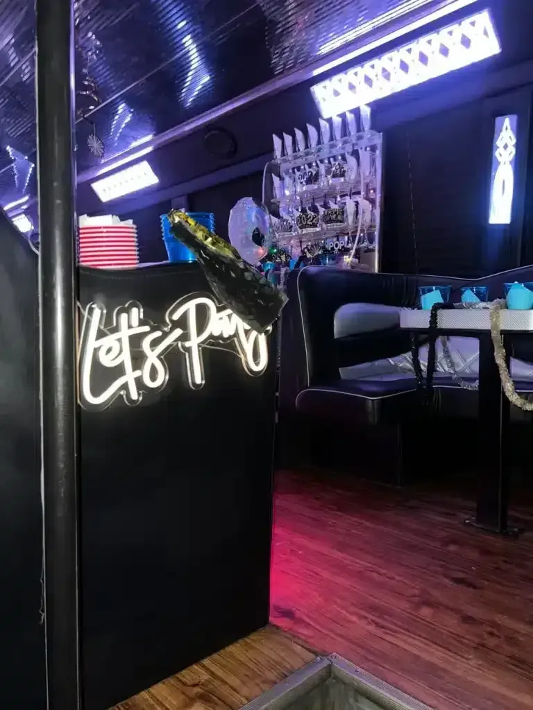 Neon-lit bar interior with a glowing sign, purple lighting, stools, and wood flooring