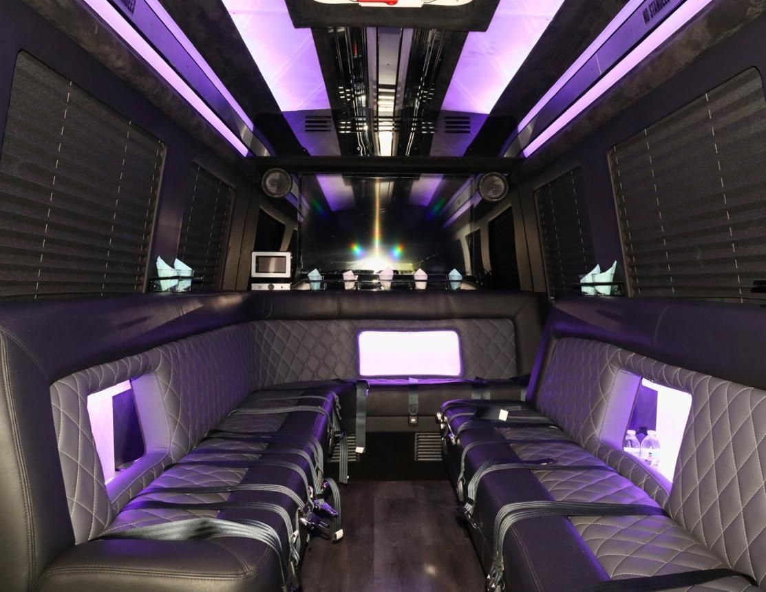 Luxury limo interior with purple lighting, quilted black seats, and a central aisle
