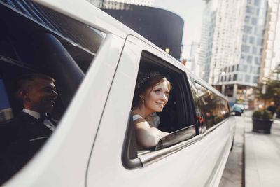 Bride looking out of a white limousine window in a city street