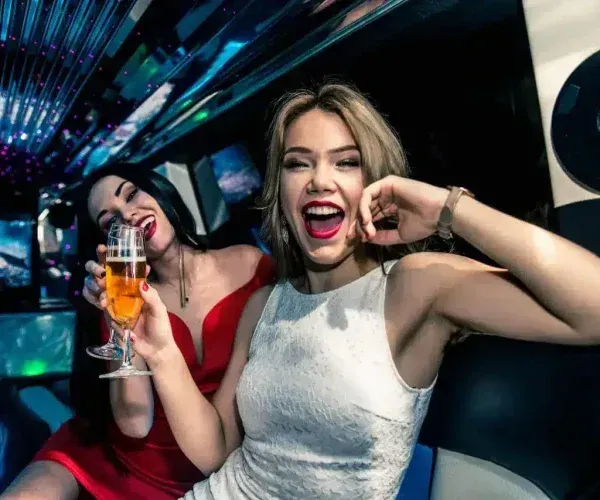 Two women celebrating in a nightclub, one holding a drink and smiling brightly