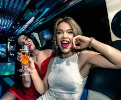 Two women celebrating in a nightclub, one holding a drink and smiling brightly