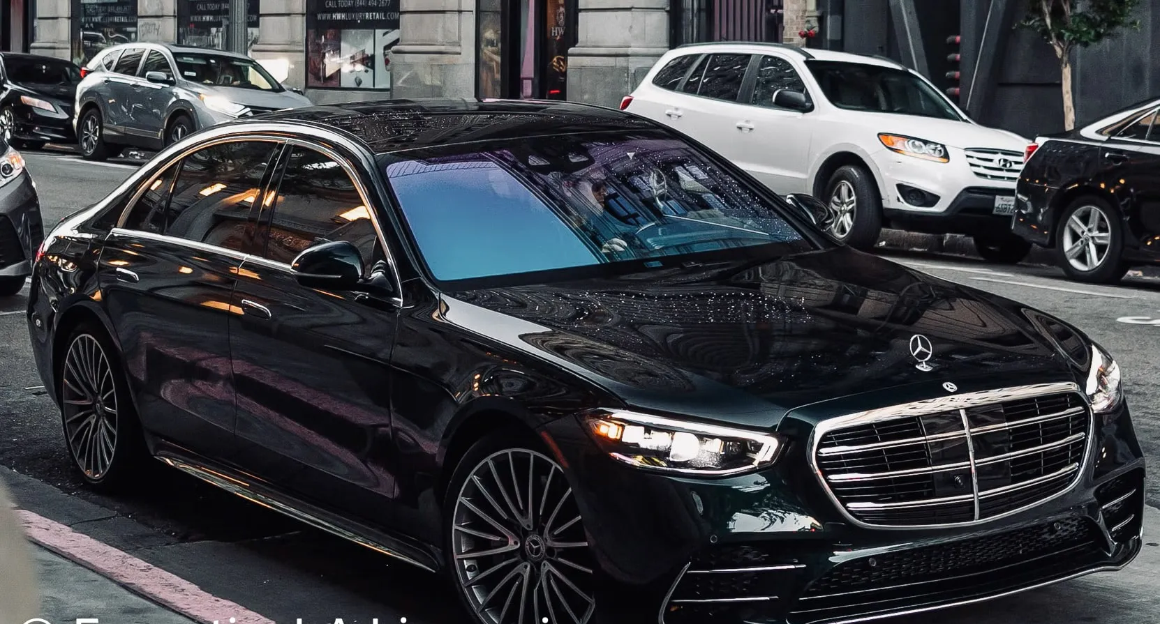 Black Mercedes sedan parked on a city street with other cars in the background