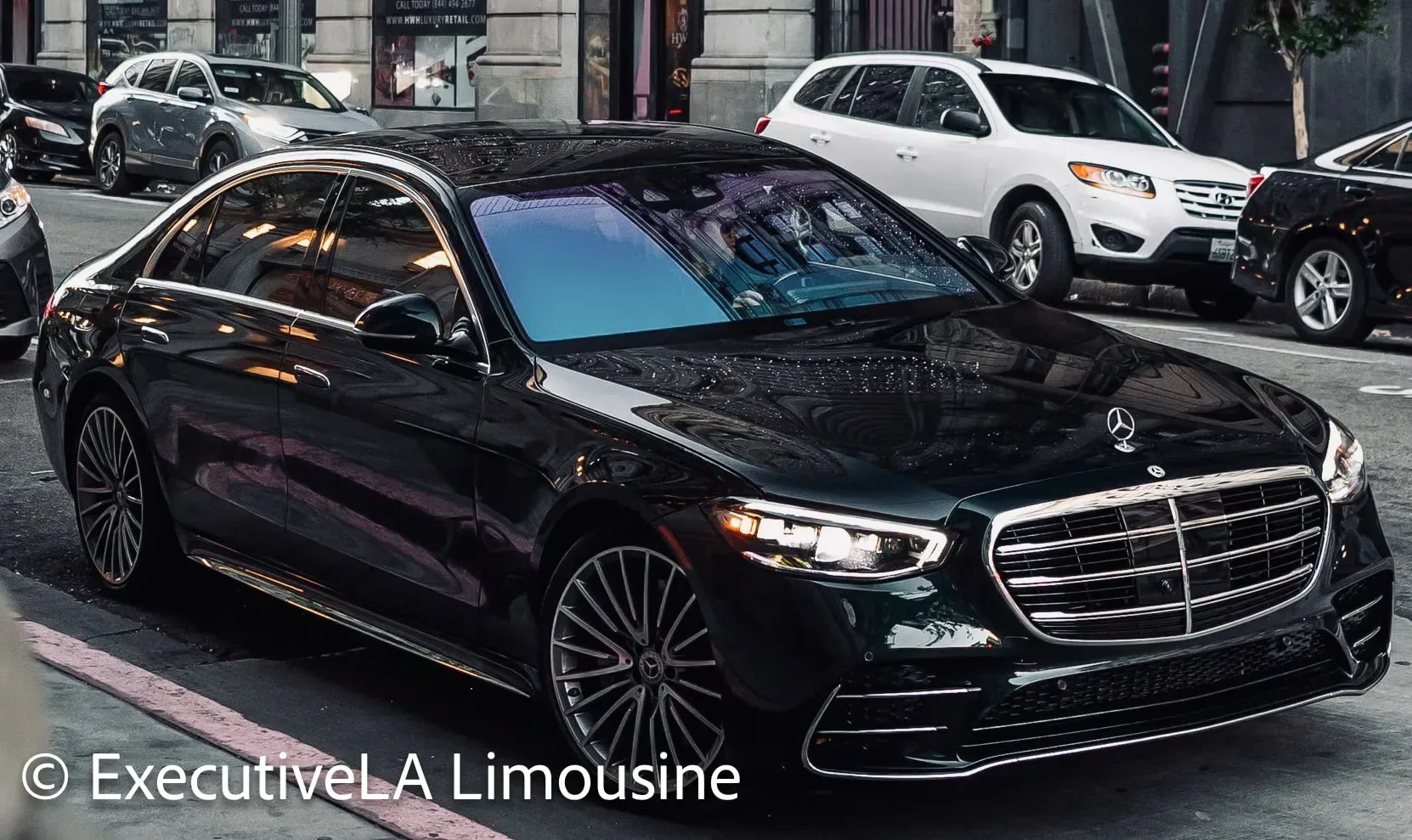 Black luxury sedan parked on a city street, with chrome grille and other cars in the background
