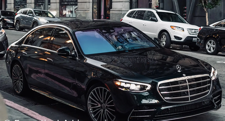 Black Mercedes sedan parked on a city street with other cars in the background