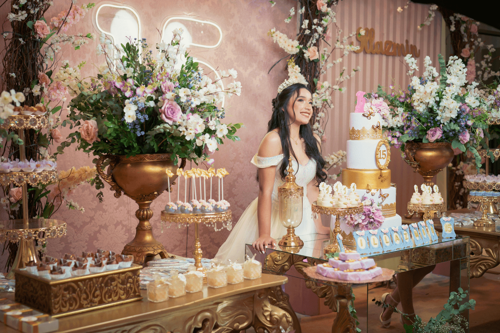 Woman at a lavish pastel dessert table with cakes, pastries, and floral arrangements in a decorated venue