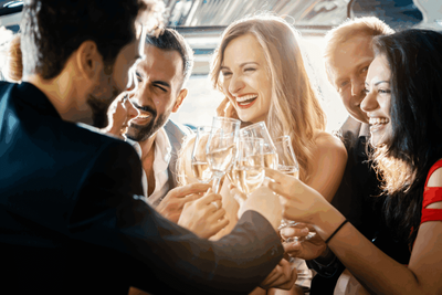 People clinking champagne glasses and smiling at a lively social gathering