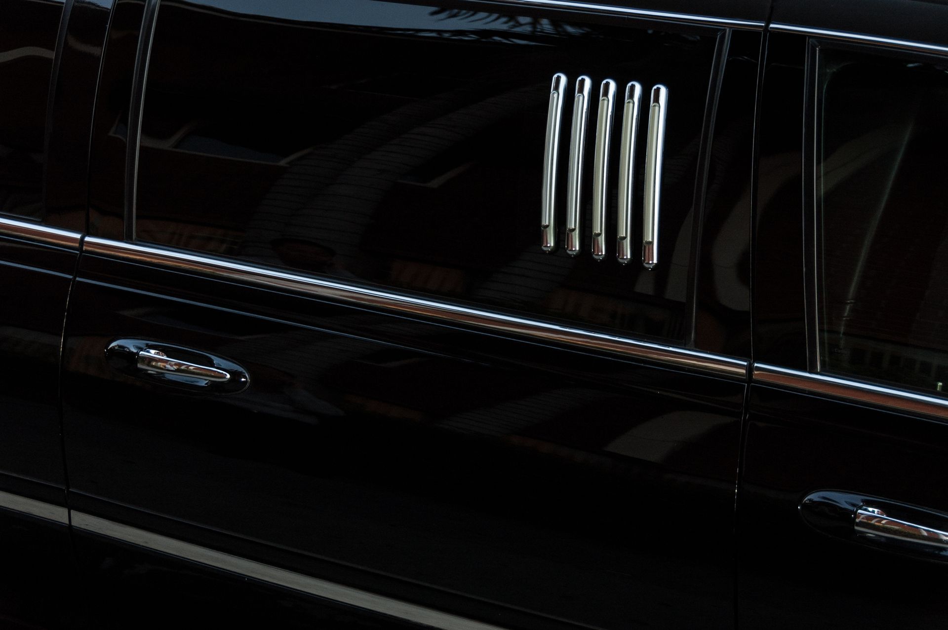 Black luxury car side panel with chrome vents and door handles