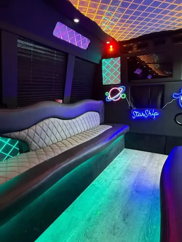 Neon-lit party bus interior with tufted bench seating and colorful LED floor lighting.