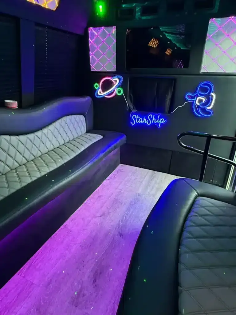 Neon-lit lounge with black leather seating, white quilted bench, and glowing wall art in purple and green.