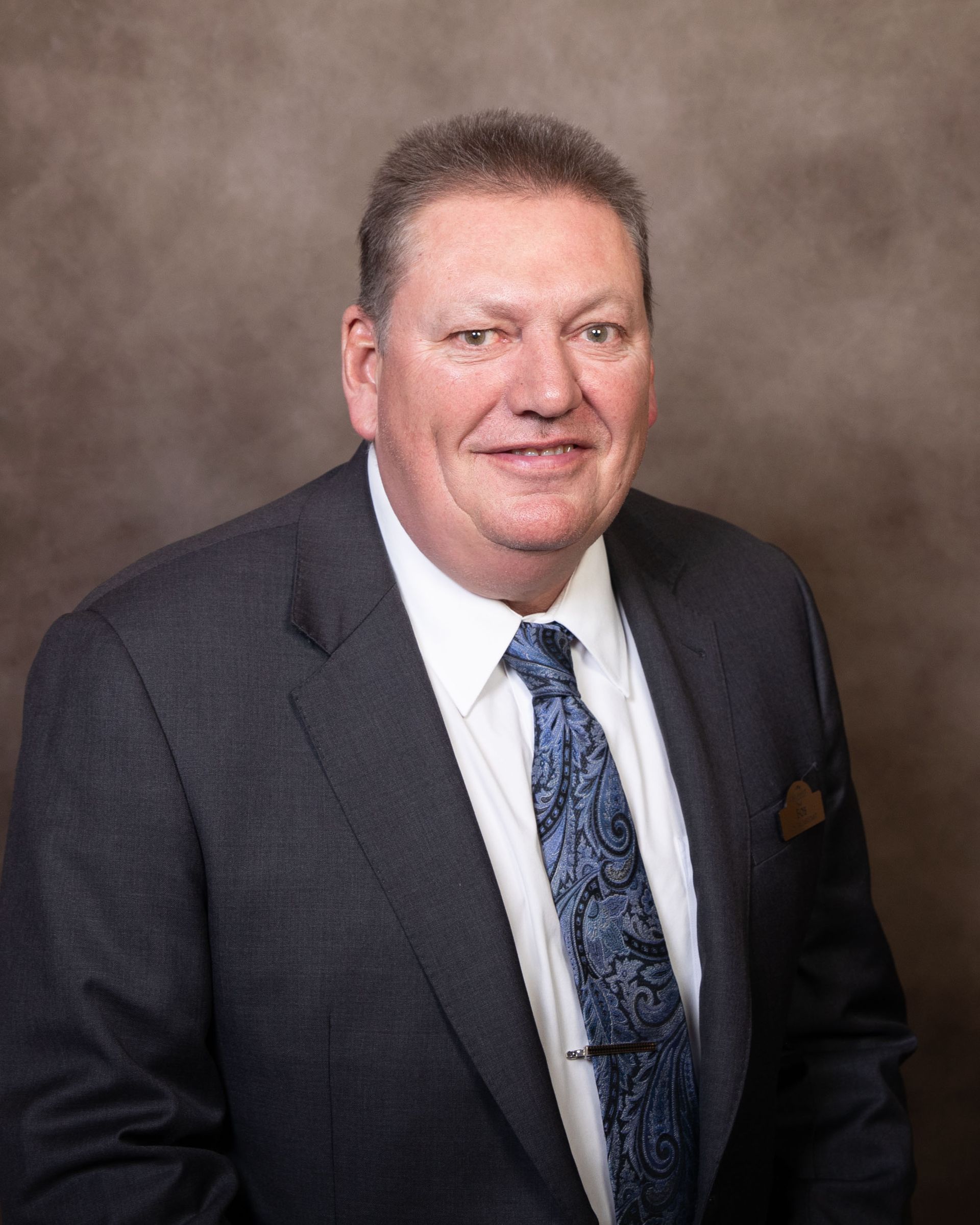 A man in a suit and tie is smiling for the camera.