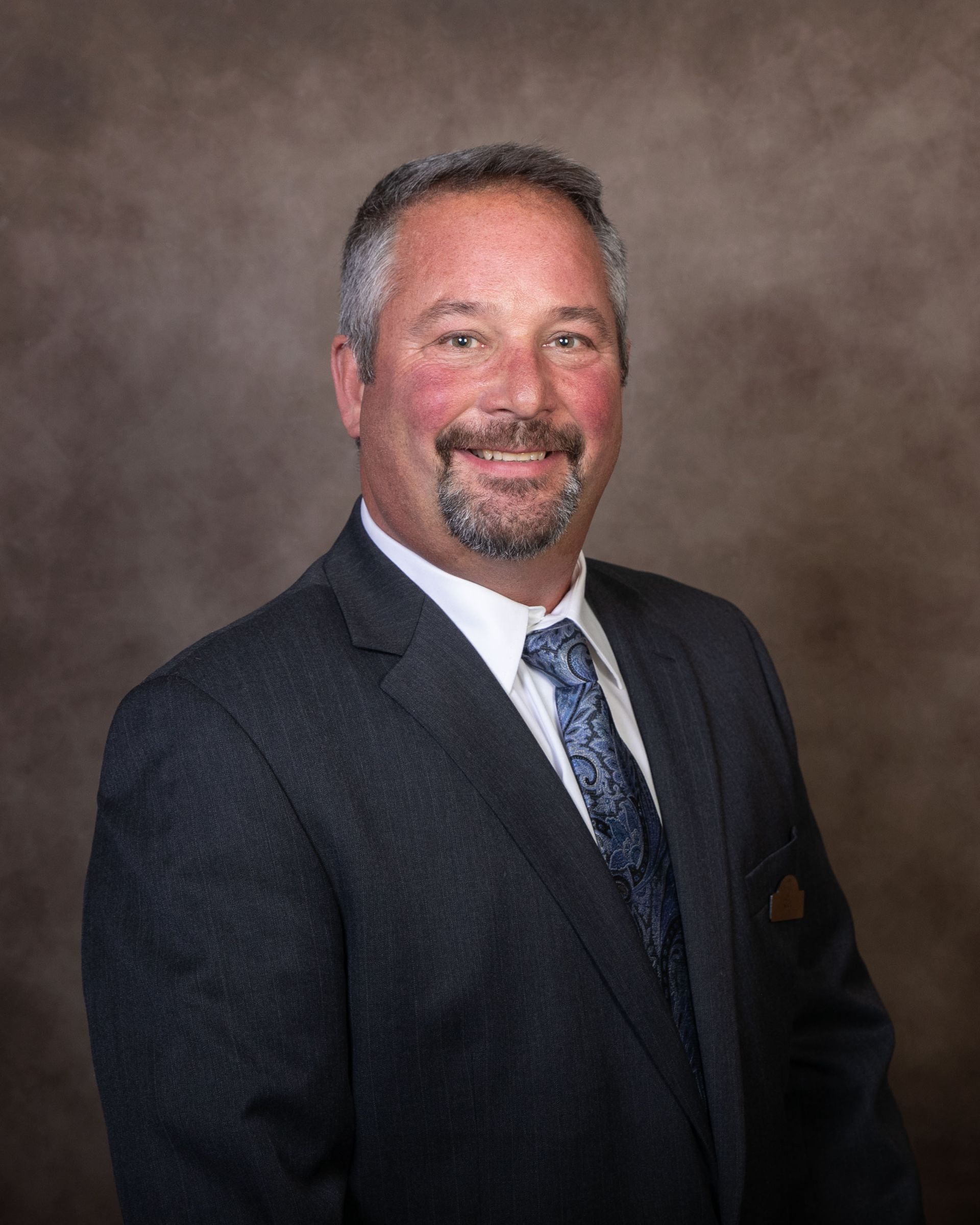 A man in a suit and tie is smiling for the camera.