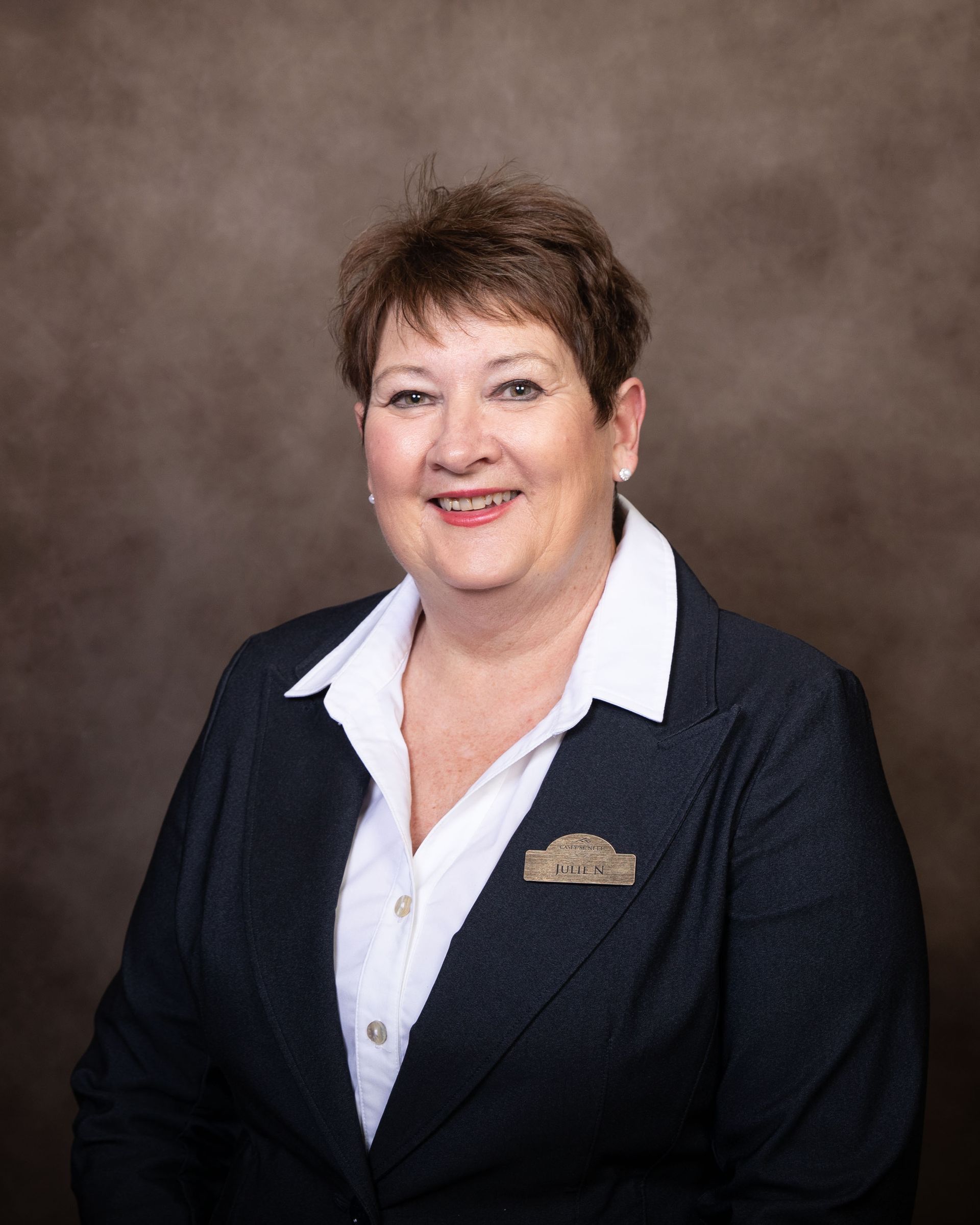 A woman in a suit and white shirt is smiling for the camera.